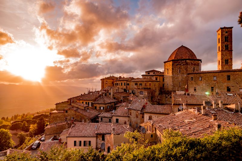 Kvllssolen lyser dramatiskt igenom molnen och ger ett rdaktigt sken ver staden Volterra i Toscana. 